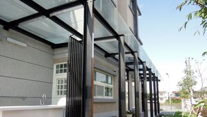 Un espace bar extérieur moderne, doté d’une structure vitrée, d’une terrasse en bois et d’un petit coin salon.