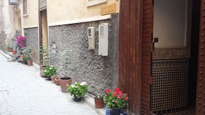 A narrow street with potted plants lining the sidewalk and a building entrance with a decorative door. - Riad Dar Cordoba (Fes)