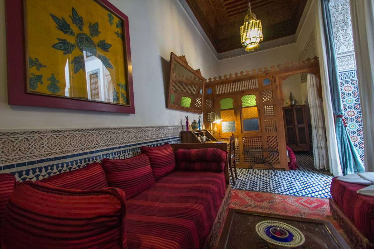 Una habitación tradicional con un sofá rojo, un espejo grande y un tapete estampado.
