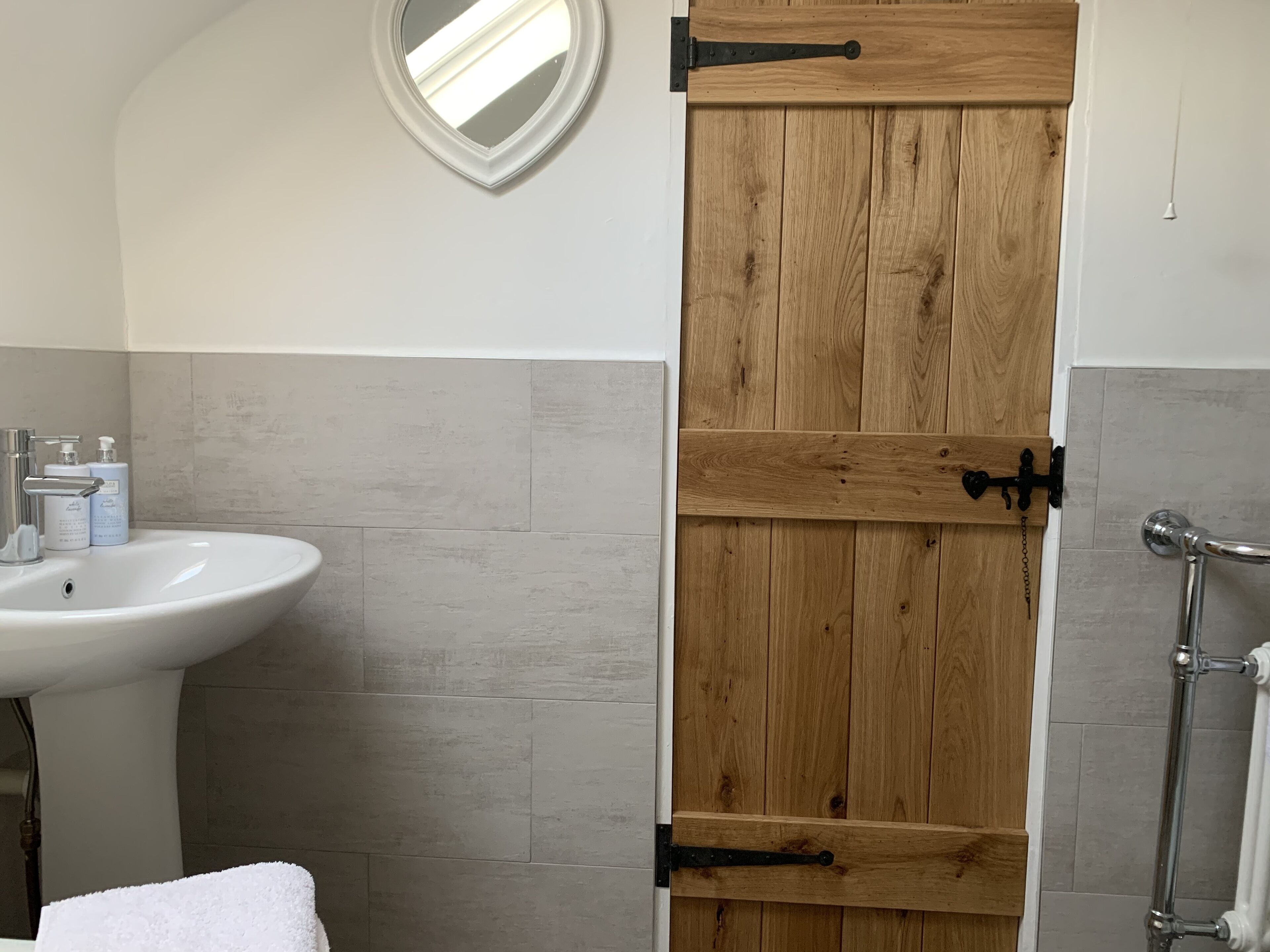 A bathroom with a wooden door, a sink, and a mirror.