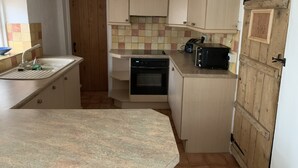 A compact kitchen with a sink, stove, and toaster. - Bell Cottage (Bury St Edmunds)