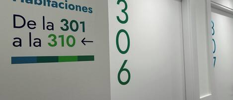 Un pasillo con los números de habitación del 301 al 310 y un letrero que indica 'Habitaciones'.