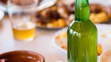 A table with a green bottle, a glass of yellow liquid, and various dishes including bread and olives.
