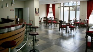 Un hall de hotel con mostrador de recepción, varias mesas de comedor con sillas y un mostrador de registro.