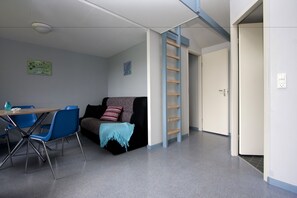 Une pièce moderne comprenant un canapé, une table à manger avec des chaises, une échelle et une porte.