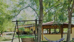 A wooden swing set, a hammock, and a covered seating area in a lush garden. - B&B Donna Maja (Centola)