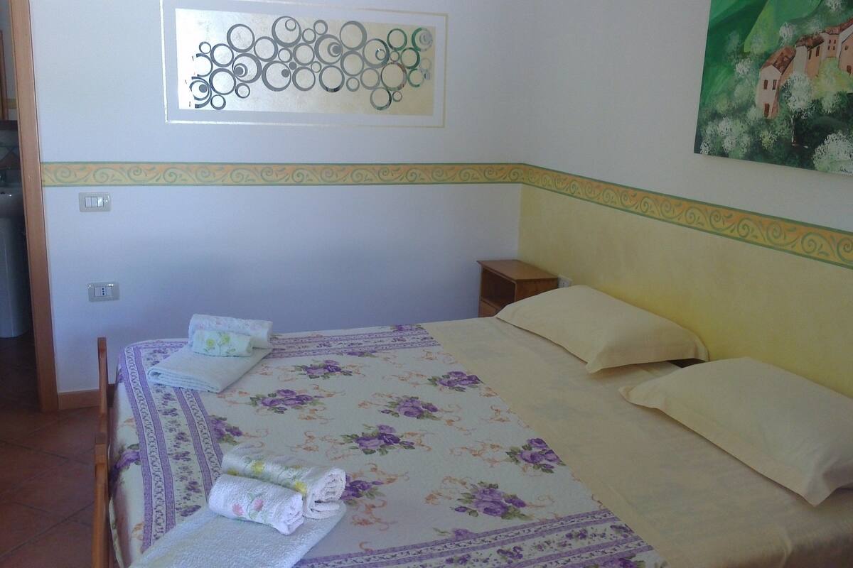 Une chambre à coucher avec un lit, des oreillers, un élément de décoration murale et un tableau.
