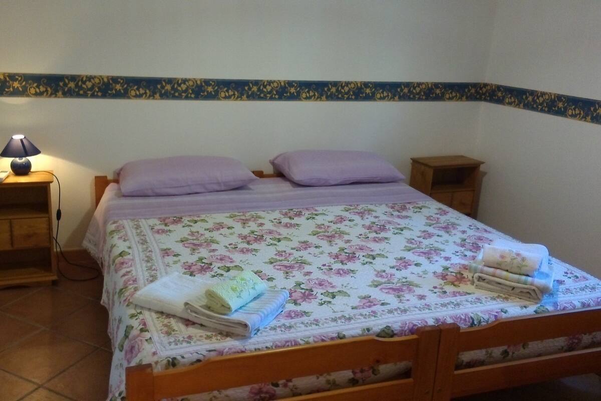 Une chambre à coucher avec un lit en bois, deux tables de chevet, une lampe et une couvre-lit à motifs floraux.