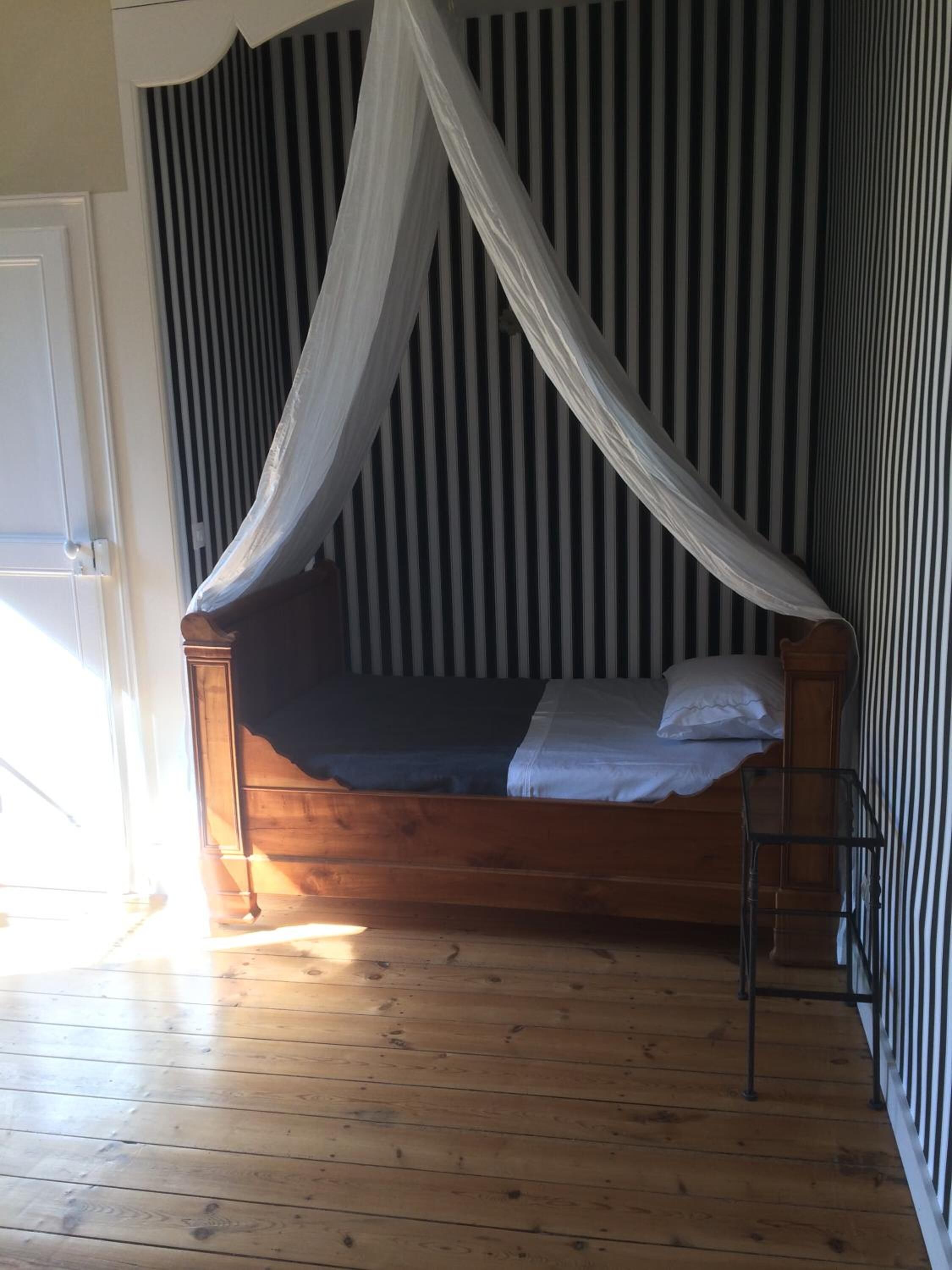 A single bed with a wooden frame and a white canopy.