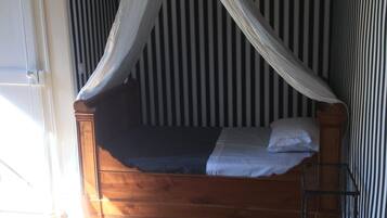 A single bed with a wooden frame and a white canopy.