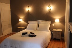 Quarto de hotel com uma cama grande, duas mesas de cabeceira com luminárias, um guarda-roupa e um espelho.