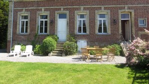 A two-story brick house with a front porch, a dining table, and outdoor seating. - Le Clos Boutenelle (Eperlecques)