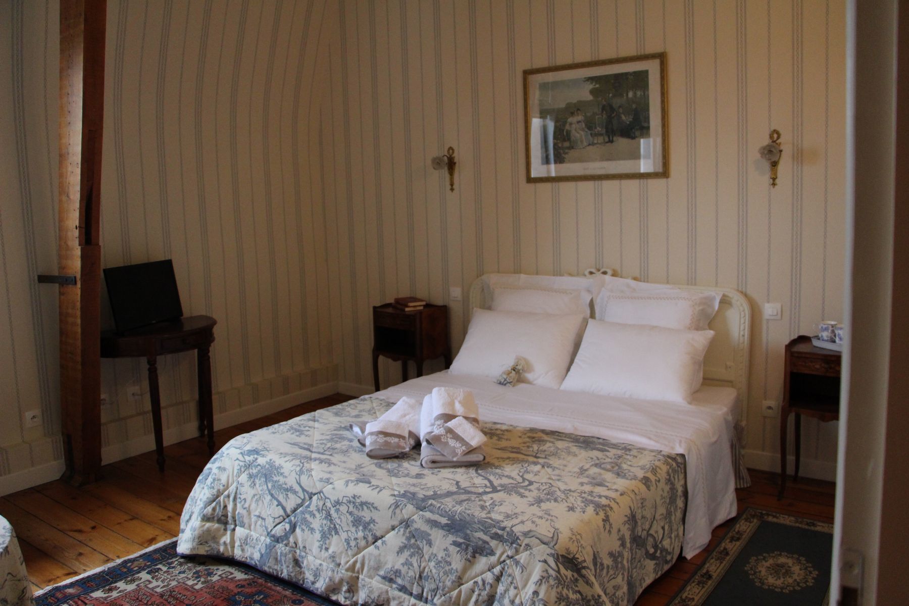 Un dormitorio ordenado con una cama, una mesita y una silla.