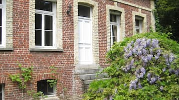 A brick building with three white-framed windows and a small door.