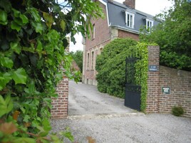 Uma entrada de cascalho leva a um edifício de tijolos, com um portão preto e uma placa com a inscrição 'La Cure Montrose'.