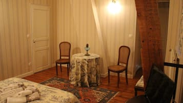 Une pièce comprenant un lit, deux chaises, une petite table avec une lampe et un tapis à motifs.