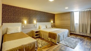 Habitación de hotel con dos camas individuales, suelo de madera, pared con diseño y ventana con cortinas.