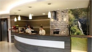 Un mostrador de recepción con un fondo de pared de piedra, tres lámparas colgantes y una chimenea.