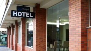 Un hotel con entrada de vidrio, un letrero que indica 'di Capri', y fachada de ladrillo.