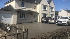 Une maison à deux étages avec un garage, des voitures garées et un panneau indiquant un espace de stationnement pour les invités.