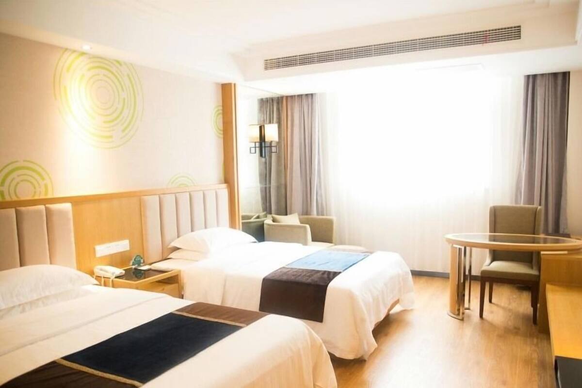 A hotel room with two beds, a desk, and a chair.