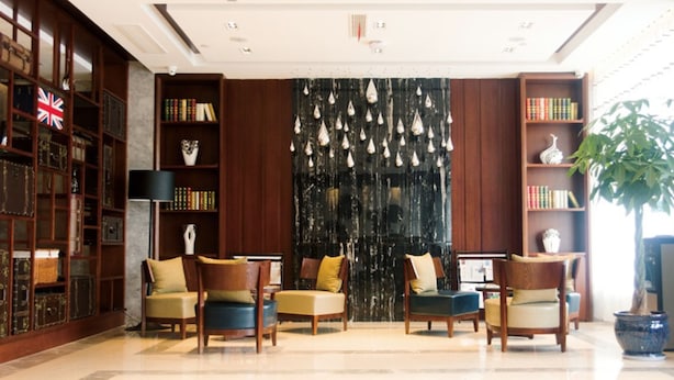 A lobby with a large bookshelf, a black decorative wall, and a potted plant. - GreenTree Inn Taizhou Taixing Middle Guoqing Road Business Hotel (Taizhou)