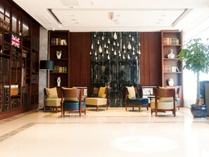 A lobby with a large bookshelf, a black decorative wall, and a potted plant. - GreenTree Inn Taizhou Taixing Middle Guoqing Road Business Hotel (Taizhou)