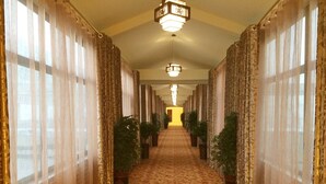 A long, narrow hallway with patterned carpet, large windows with sheer curtains, and potted plants on either side. - GreenTree Inn Suqian Sihong Passenger Station Zhongyuan Logistics District Hotel (Suqian)