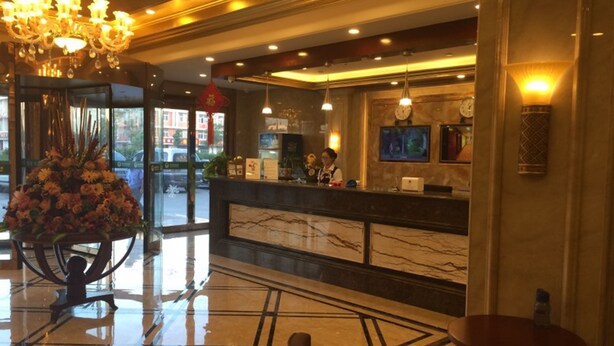 A hotel lobby with a marble reception desk, a chandelier, and a large floral arrangement. - GreenTree Inn Suqian Sihong Passenger Station Zhongyuan Logistics District Hotel (Suqian)