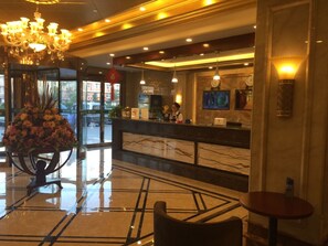 A hotel lobby with a marble reception desk, a chandelier, and a large floral arrangement. - GreenTree Inn Suqian Sihong Passenger Station Zhongyuan Logistics District Hotel (Suqian)