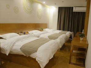 Hotelkamer met twee bedden, een houten hoofdbord, een nachtkastje met een plant en een wand met ronde patronen.