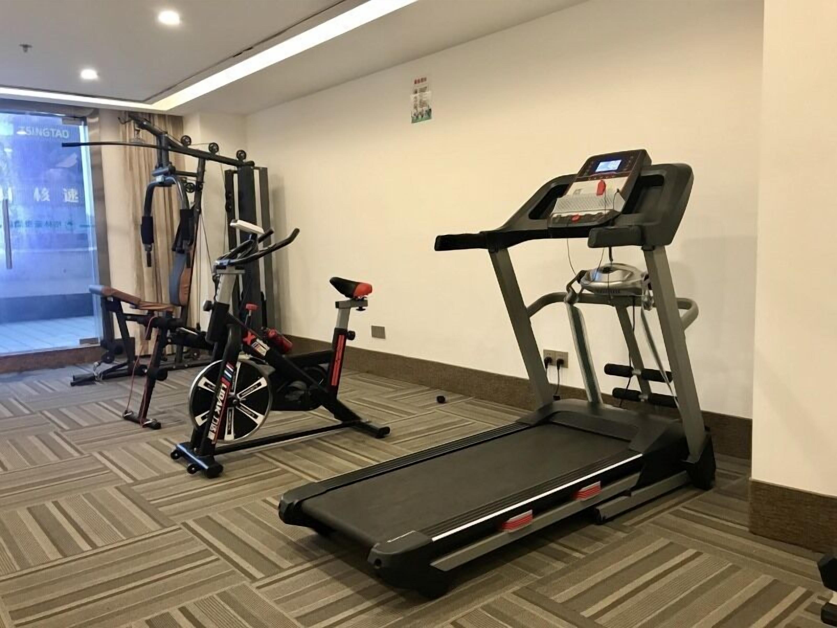 A fitness room with a treadmill, stationary bike, and weight machine.