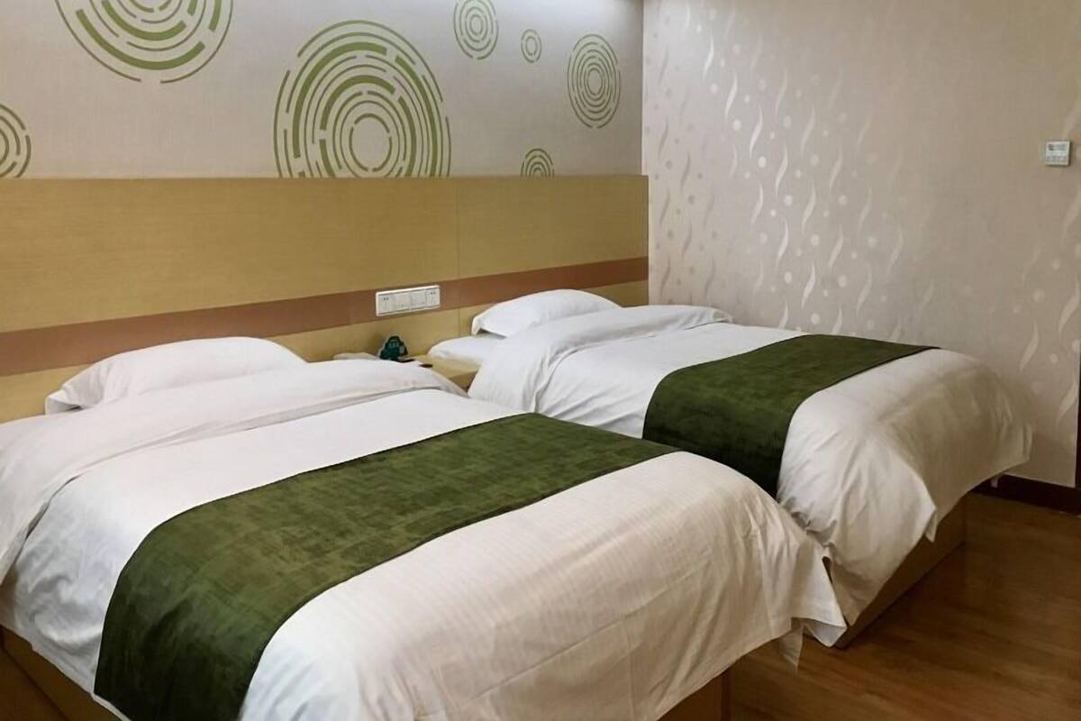 Habitación de hotel con dos camas, cabeceros, mesitas de noche y una pared con diseños circulares.