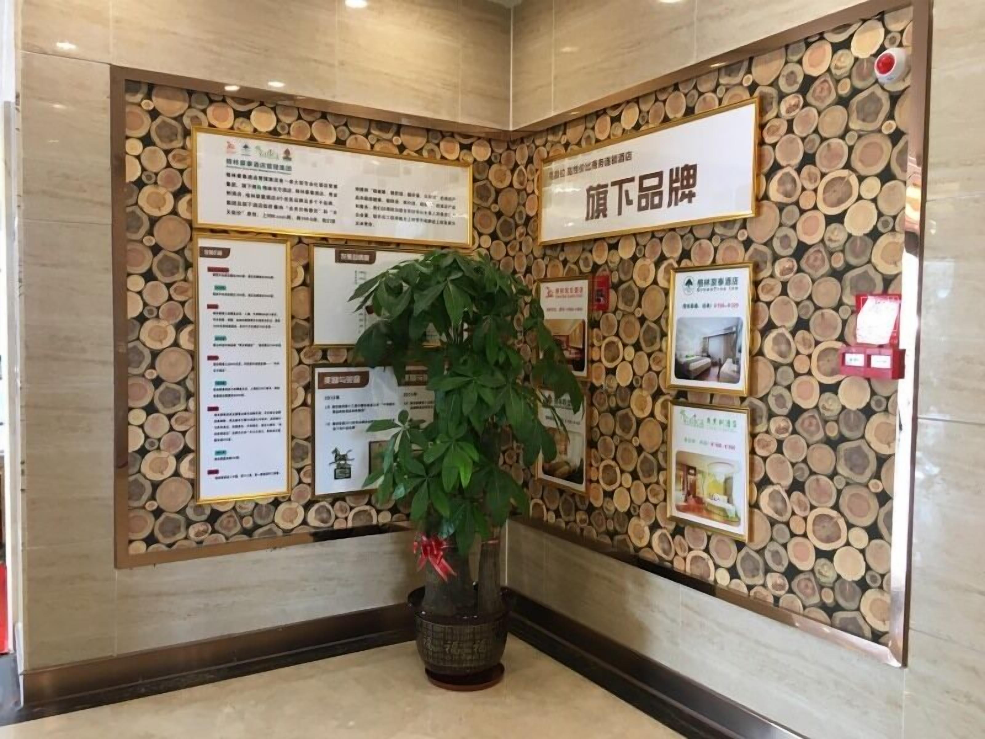 Un hall d’entrée avec un mur décoré de rondins de bois, des panneaux d’information et une plante en pot.
