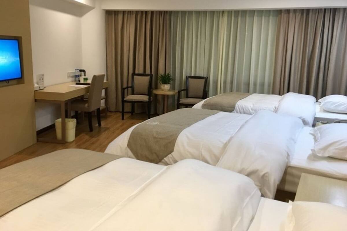 Habitación de hotel con dos camas, un escritorio, sillas, un televisor y un telón de fondo.