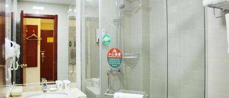 A hotel bathroom with a glass-enclosed shower, a sink with toiletries, and a towel rack.