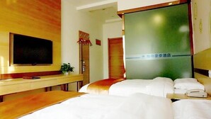A hotel room with a bed, a desk with a television, and a green wall with a sign. - GreenTree Inn Langfang GuAn County Xinyuan Street Express Hotel (Langfang)