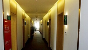 A hotel hallway with doors marked by numbers, a fire hydrant sign, and a potted plant. - GreenTree Inn Langfang GuAn County Xinyuan Street Express Hotel (Langfang)