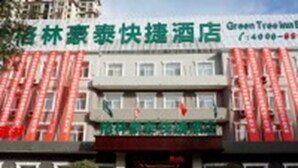 A hotel with a red facade and multiple windows. There are cars parked in front. - GreenTree Inn Langfang GuAn County Xinyuan Street Express Hotel (Langfang)