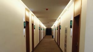 Un couloir d’hôtel avec des portes indiquant les numéros des chambres et un sol recouvert de moquette.