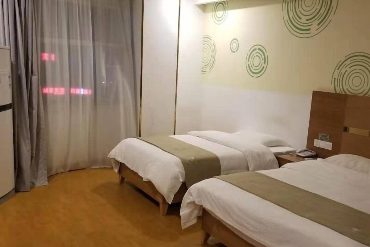 Ein Hotelzimmer mit zwei Betten, Holzboden und einer Wand mit kreisförmigen Mustern.