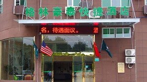 L’entrée d’un hôtel, avec une enseigne en langue étrangère, des drapeaux et des unités de climatisation.