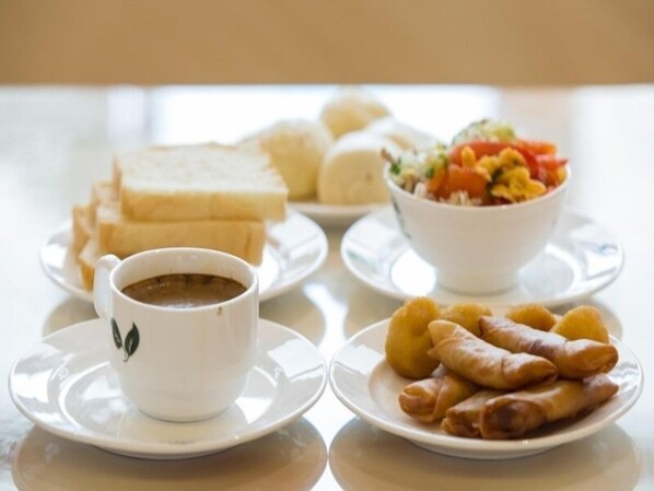 A table with a cup of coffee, a plate of spring rolls, a bowl of salad, and a plate of bread. - GreenTree Inn Maanshan Hanshan District Jiuwu Square Hotel (Ma'anshan)