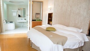 Una habitación de hotel con una cama grande, un baño con bañera y un espejo.