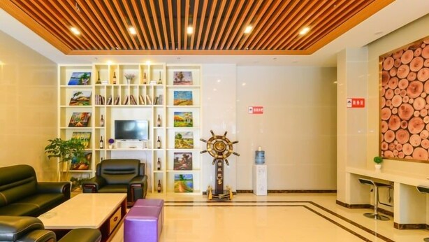 A hotel lobby with a wooden ceiling, a reception desk, a television, a ship's wheel decoration, and a bookshelf with various items. - GreenTree Inn Wuhu Fangte Four Phase Wanchun Fortune Plaza Hotel (Wuhu)