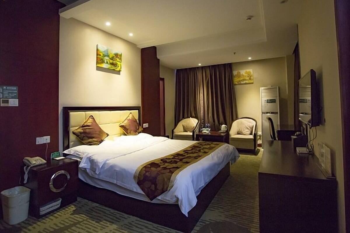 Una habitación de hotel con una cama grande, un escritorio, una silla, un espejo y un televisor.