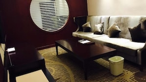 A modern living room with a round window, a sofa with cushions, a coffee table, and a trash bin. - GreenTree Alliance Chuzhou Laian County Development District Jingyi Road Hotel. (Chuzhou)