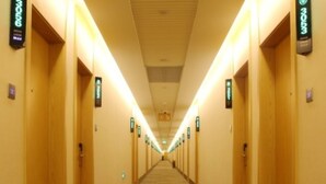 A hotel hallway with doors on both sides, illuminated by overhead lights, and a patterned carpet. - Greentree Inn Anhui Anqing Susong North Longmen Rd (Anqing)