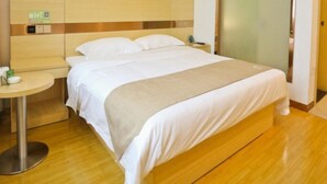 A hotel room with a bed, a bedside table, a wall with circular patterns, and a door with frosted glass. - Greentree Inn Anhui Anqing Susong North Longmen Rd (Anqing)