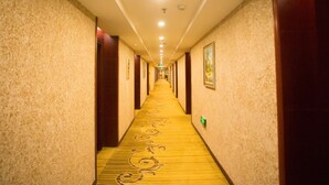 Ein Hotelkorridor mit Teppichböden, Holztüren und gerahmten Bildern an den Wänden.